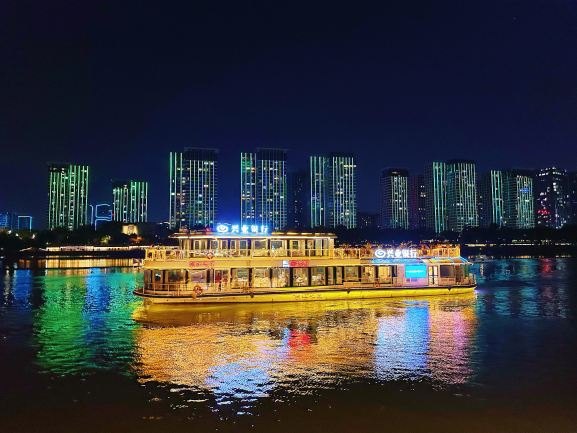 福州闽江夜游游船行驶在江面上，两岸高层建筑灯光倒映水中