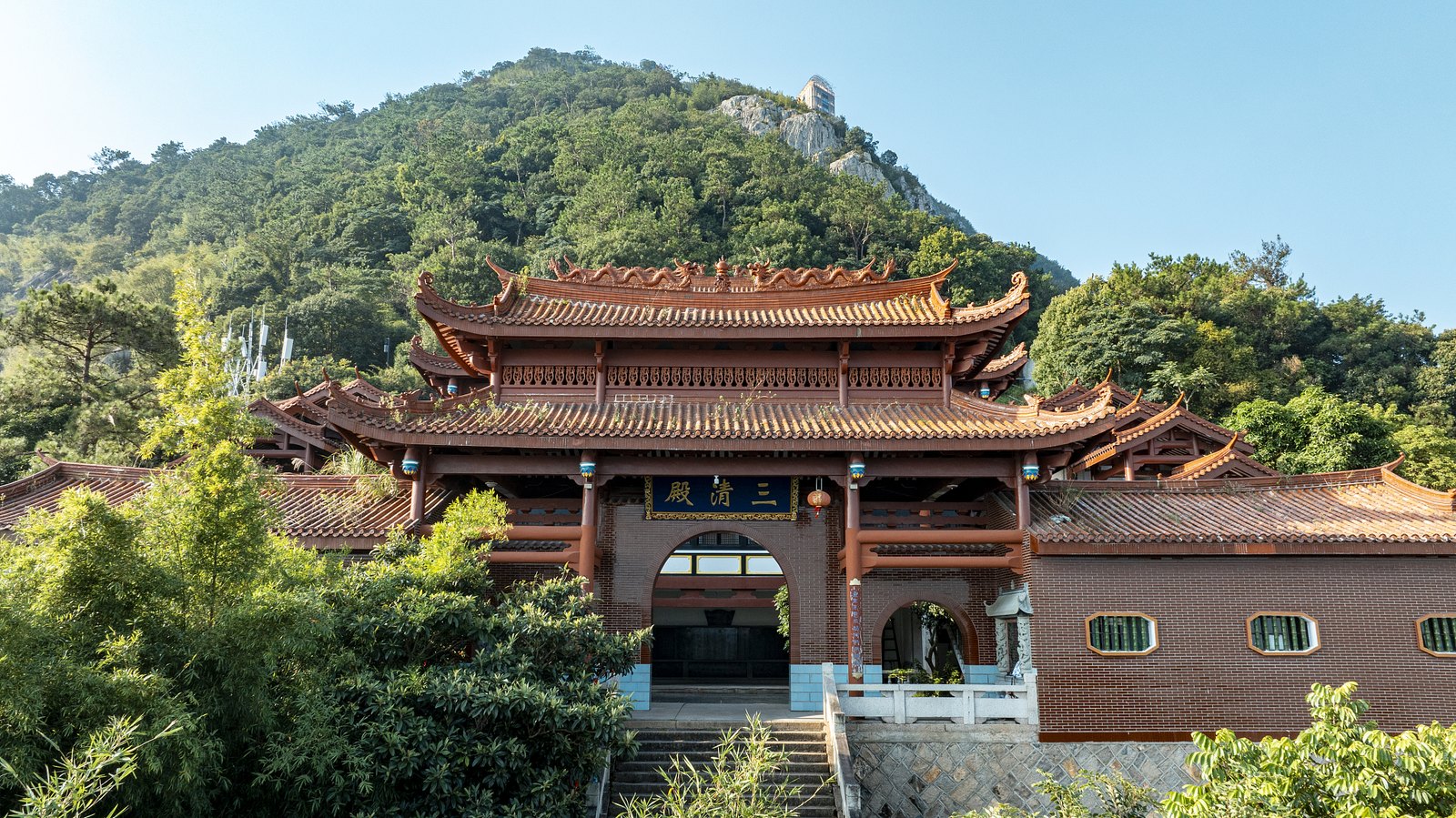 永泰青云山三清殿的朱红殿门与层叠瓦顶，背后是绿色山体